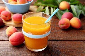Apricot juice in glass, fresh fruits and leaves on wooden table, closeup © New Africa