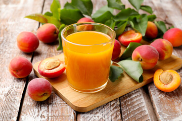 Apricot juice in glass, fresh fruits and leaves on wooden table, closeup © New Africa