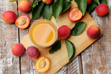 Apricot juice in glass, fresh fruits and leaves on wooden table, flat lay © New Africa