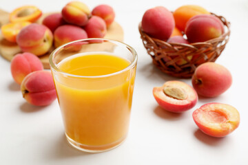 Apricot juice in glass and fresh fruits on white table, closeup © New Africa
