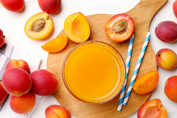 Apricot juice in glass, fresh fruits and drinking straws on white marble table, flat lay © New Africa