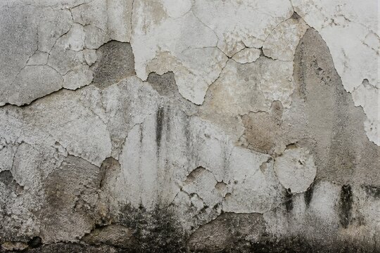 Cracked plaster reveals weathered textures beneath. Streaks of grime mark time's passage on the wall. Damp patches hint at moisture's persistent presence