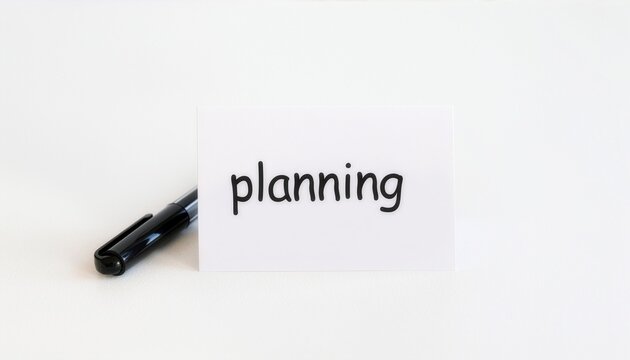Conceptual White Card with the Word Planning Displayed Alongside a Black Ink Pen on a Minimalist Surface