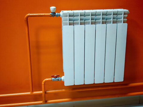 Sectional radiator (aluminium or bimetallic), wall-mounted with side pipe connections and shut-off valves.