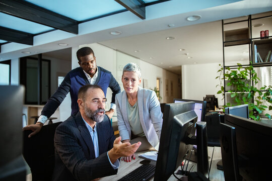 Business team collaborating at computer in modern office