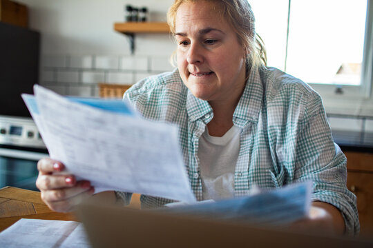 Worried woman reviewing household bills at kitchen table