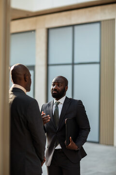 Two businessmen discussing project outside modern office building