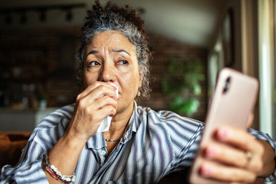 Upset senior woman crying during phone call at home