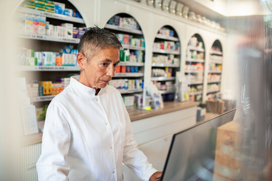 Pharmacist using computer at pharmacy counter
