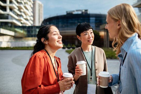 Three businesswomen networking with coffee at an outdoor conference