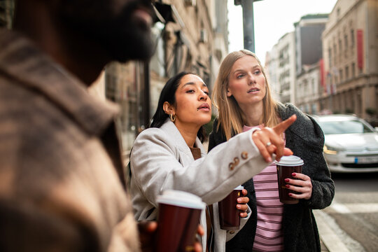 Friends with coffee pointing the way on city street