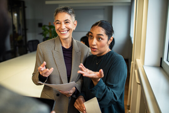 Two colleagues discussing paperwork in modern office