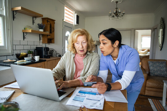 Caregiver helps senior woman manage online bills at home