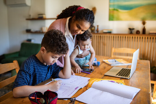 Mother helping son with homework at kitchen table
