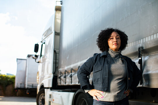Confident female truck driver standing by semi at freight yard