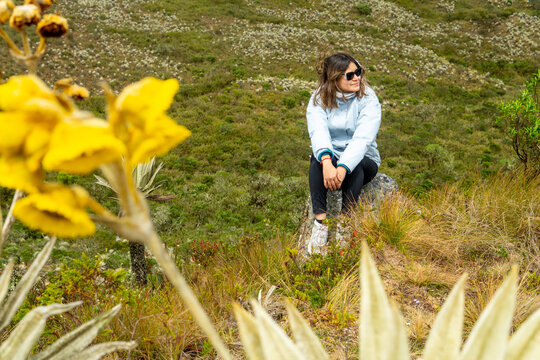 Woman hiking in colombian paramo looking at frailejon plants
