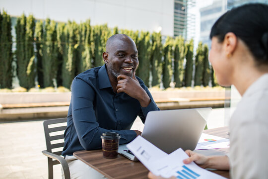 Colleagues discussing charts during outdoor office meeting