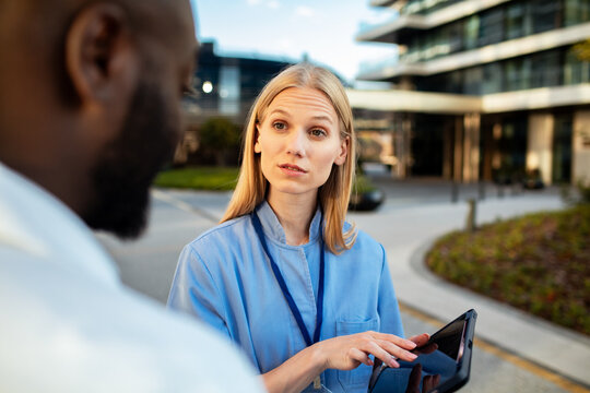 Healthcare worker discussing patient notes with colleague outside hospital
