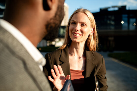 Smiling businesswoman greeting colleague outside office