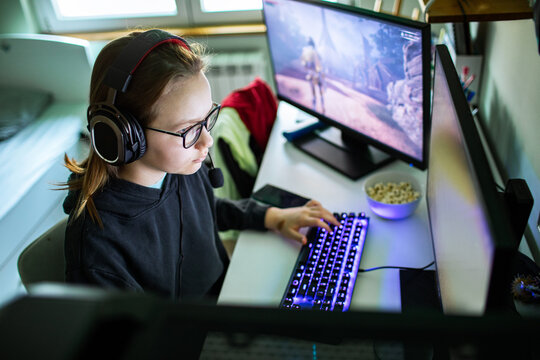 Teen gamer with headset playing pc game at home