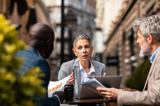 Senior businesswoman leading meeting at outdoor city cafe
