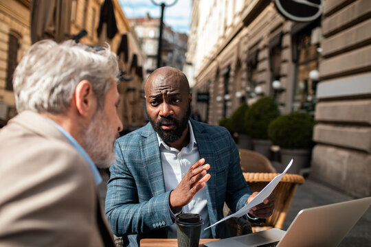 Two business colleagues discussing documents at outdoor cafe