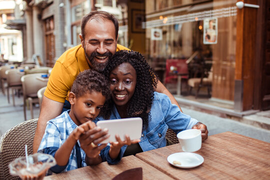 Happy family watching smartphone at outdoor cafe