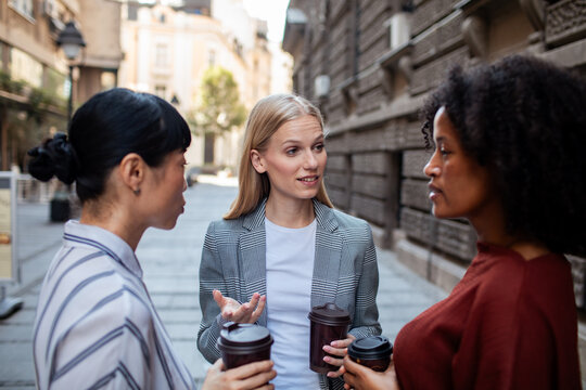 Three businesswomen networking over coffee on city street