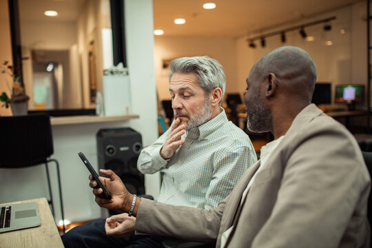 Two colleagues reviewing a smartphone in modern office