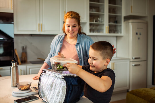 Parent and child packing school lunch in modern home kitchen