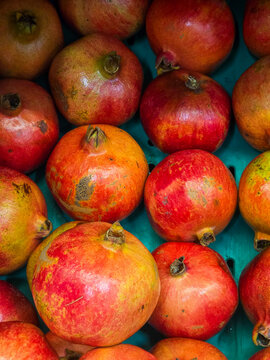 Fresh red pomegranates displayed in market crate top view close up