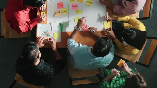 Top view of people writing and making scrum task board while writing marketing and planning strategy at colorful sticky notes. Smart team manage work performance by using kanaban board. Convocation.