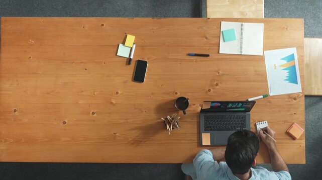 Manager talking to boss by using phone while diverse team sharing idea or financial chart in tablet. Top view of diverse people brainstorming and sharing plan while man talking to phone. Convocation.