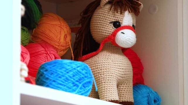 A crocheted stuffed horse sitting in a closet