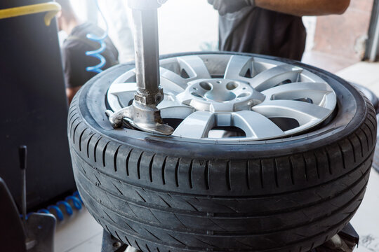 Tire mounting service with mechanic fitting rubber onto alloy rim using tire changer, automotive workshop maintenance for replacement, wheel repair and safe driving.