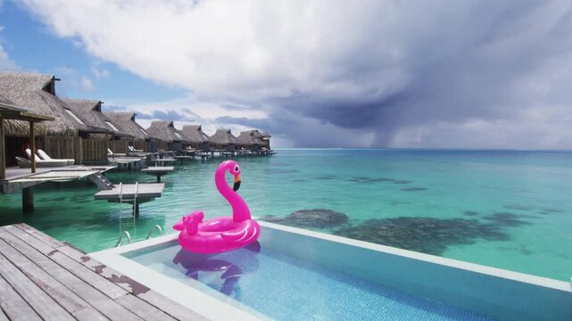 Holidays Vacation Getaway Concept. Funny vacation beach pool travel concept with inflatable pink flamingo float toy mattress in luxury swimming pool. SLOW MOTION