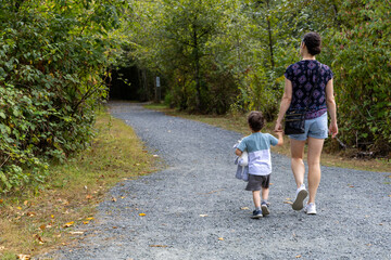 Fototapeta premium Mother And Son Walking Hand In Hand On Woodland Trail At Great Blue Heron Nature Reserve, Chilliwack, BC