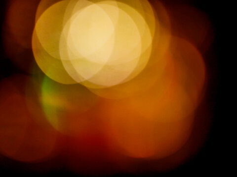 Warm glowing bokeh lights blend in dark background. Abstract light circles show soft golden, orange, and red hues. Perfect for festive, romantic, or atmospheric backgrounds. Great for holiday cards