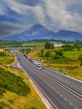 Motorway with a government car cartage and support vehicles, Picturesque mountains and cloudy sky in the background. High value VIP travel for a business meeting. Security and safety in transit.