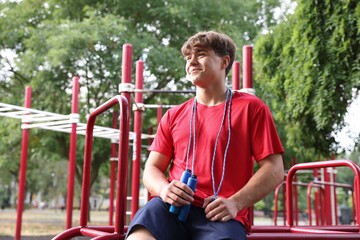 Fototapeta premium Teenage boy with jumping rope at outdoor sports ground. Space for text