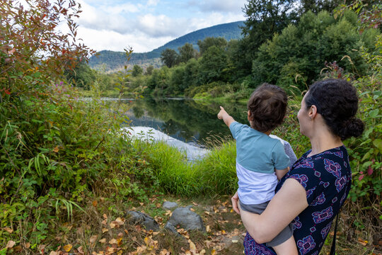 Mother Holding Child Pointing Across Peaceful Lake at Great Blue Heron Nature Reserve in Chilliwack, BC Canada