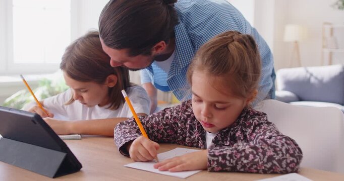 Father helping kids in family home education, preschooler homeschooling parent and children learning distant class, write, study, doing homework together using tablet, kissing to express love