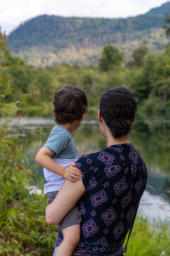 Mother Carrying Young Child Overlooking Lake At Great Blue Heron Nature Reserve In Chilliwack, BC Canada