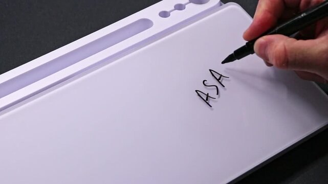 European male hand writing ASAP on whiteboard with black pen and erases it with white sponge afterwards for seamless looping message writing on whiteboard. ASAP very urgent text