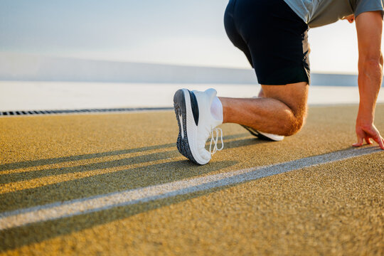 Runner prepares for a sprint on a sunlit track with determined focus and energy