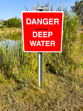 A red warning sign warns people of deep water