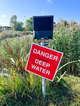 A red warning sign warns people of deep water