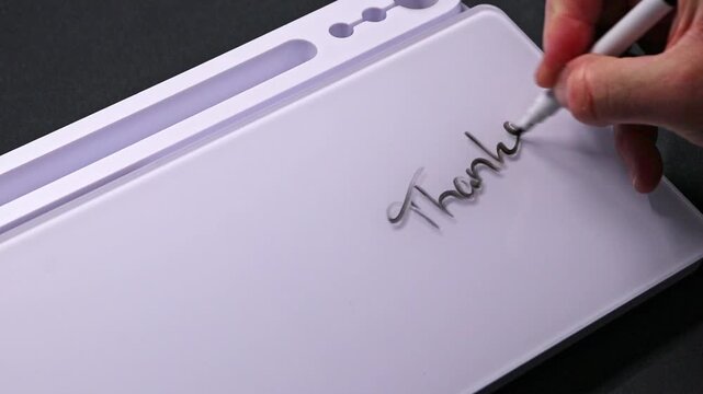 European male hand writing thanks on whiteboard with black pen and erases it with white sponge afterwards for seamless looping message writing on whiteboard. Thank you message text.