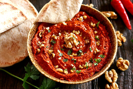 Muhammara dip in a bowl served with pita bread and walnuts. Middle Eastern mezze.
Traditional Middle Eastern muhammara dip made of roasted red peppers, walnuts, pomegranate molasses, and olive oil. 