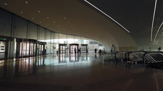 Doha, Qatar - January 20 2026: Interior view across a metro entrance hall with curved dark ceiling, linear lighting, glass doors and escalators.